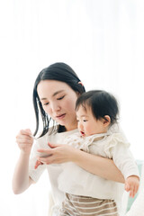 赤ちゃんに離乳食を食べさせるママ