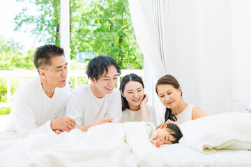 Fototapeta premium 赤ちゃんの寝顔を見守る三世代家族