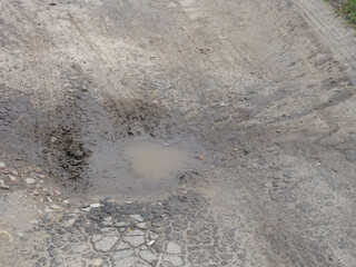 Cracked road with a muddy puddle in it.