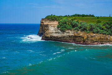 Pantai Klayar or Klayar Beach with rocks and strong waves against the blue sky