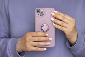 Puple silicone case with ring on new mobile phone in female hands. Faceless woman make a photo on...