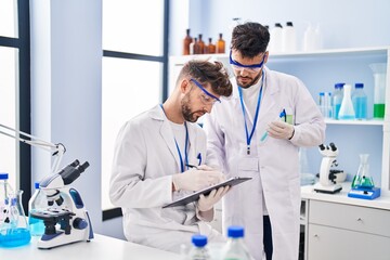 Young couple wearing scientist uniform working at laboratory
