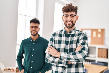 Young couple business workers standing with arms crossed gesture at office