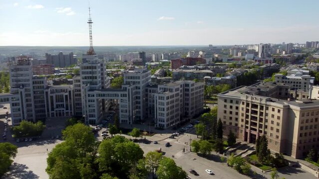 Aerial pan left to right view on Derzhprom and Karazin University northern building on Freedom Square with green park and blue sky in Kharkiv, Ukraine