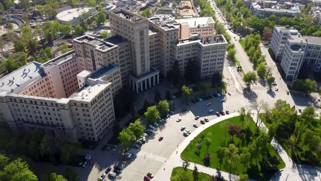 Aerial pan look down view on Derzhprom and Karazin National University buildings on Freedom Square with spring greenery in Kharkiv, Ukraine