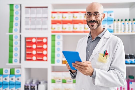Young hispanic man pharmacist using touchpad at pharmacy