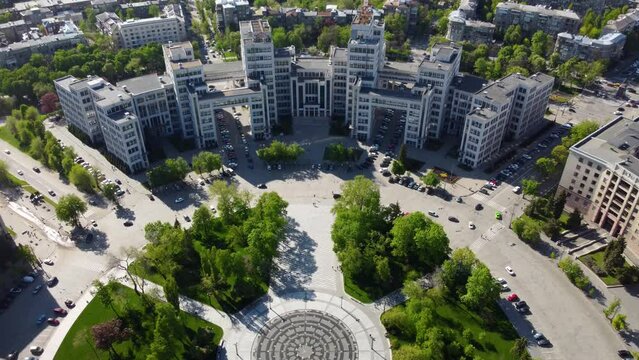 Aerial dolly, pull out view on Derzhprom building with fountain and green park in spring on Freedom (Svobody) Square in Kharkiv city, Ukraine