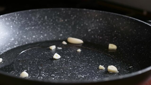 Woman puts on the pan juicy staek with rosemary and garlic, uses kitchen utensils. Process of roasted steak cooking