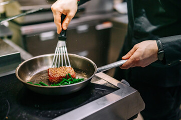 man chef cooking fried tuna fish and green bean in frying pan on kitchen