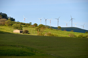 farmhouse among pastures filled with wind turbines