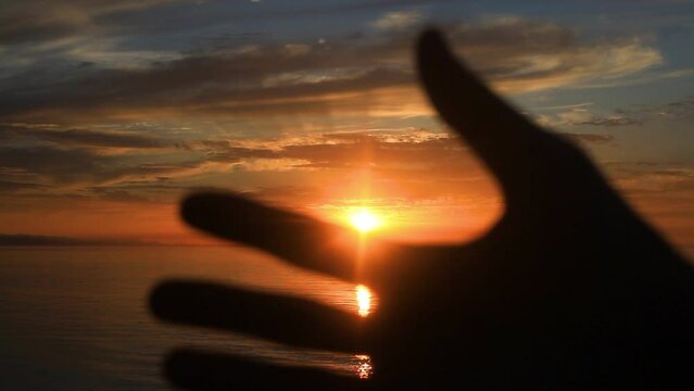 Hand Fingers waving against sun light at sunset. Close up 