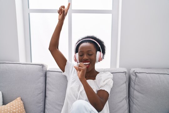 African american woman listening to music singing song at home