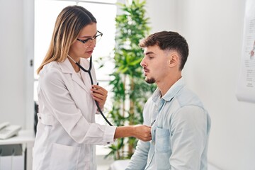 Young man and woman doctor and patient auscultating heart at clinic