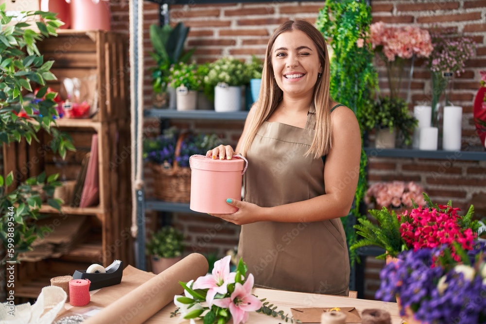 Poster Young blonde woman working at florist shop winking looking at the camera with sexy expression, cheerful and happy face.