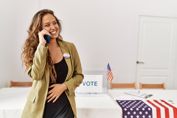 Young beautiful hispanic woman electoral table president talking on smartphone at electoral college