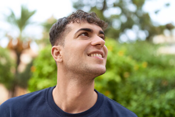 Young hispanic man smiling confident looking to the side at park