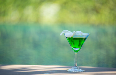 

Beautiful glass with a refresh cocktail and a pretty woman on the background of the swim pool. Top view, close-up. Vacation and travel concept. Moments of celebration