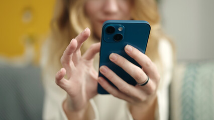 Young blonde woman using smartphone at home
