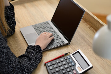 Kobieta blondynka przy biurku z laptopem i kalkulatorem  - obrazy, fototapety, plakaty