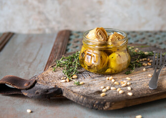 glass jar with grilled artichokes in oil on the table