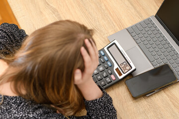 Załamana kobieta i kalkulator z laptopem przy biurku