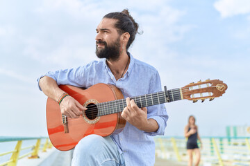 Obraz premium Young hispanic man musician playing classical guitar at seaside
