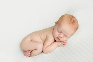 Sleeping newborn baby boy posing on white cloth.Newborn boy in the first days of life sleeps on white background.