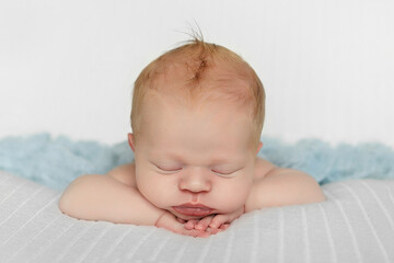 Newborn boy in the first days of life sleeps on white background.