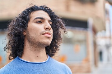 Young latin man looking to the side with serious expression at street