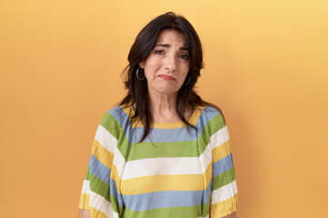 Middle age hispanic woman standing over yellow background depressed and worry for distress, crying angry and afraid. sad expression.