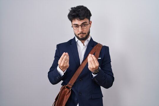 Hispanic man with beard wearing business clothes doing money gesture with hands, asking for salary payment, millionaire business