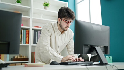 Young hispanic man student using computer studying at library university