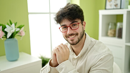 Fototapeta premium Young hispanic man smiling confident sitting on table at dinning room