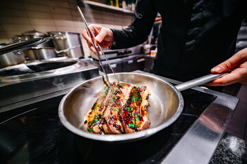 man chef cooking fried meat slice in frying pan on restaurant kitchen