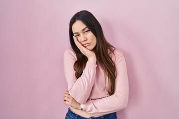 Fototapeta premium Young brunette woman standing over pink background thinking looking tired and bored with depression problems with crossed arms.
