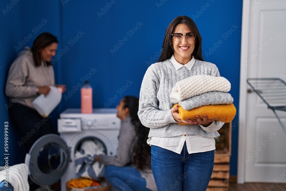 Sticker Three women doing laundry at home winking looking at the camera with sexy expression, cheerful and happy face.