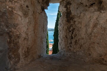 View through a gap in the wall to the blue sea with boats