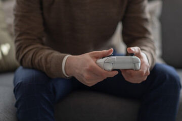 Man holding white controller in hands.  © Mads