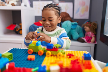 African american boy playing with construction blocks sitting on table at kindergarten