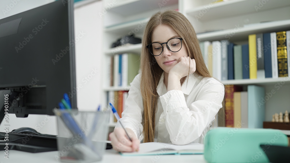 Sticker young blonde woman student using computer writing on notebook at university classroom