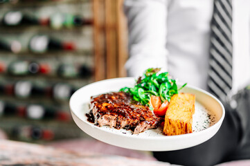 waiter hold in his hands ready beef steak ribeye meat