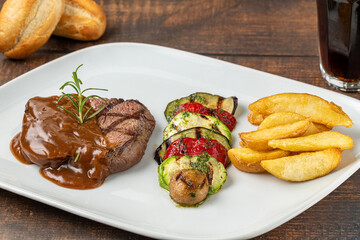 Grilled beef tenderloin with bolognese sauce with grilled vegetables on a white porcelain plate