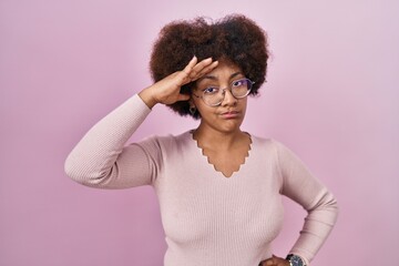 Obraz na płótnie Canvas Young african american woman standing over pink background worried and stressed about a problem with hand on forehead, nervous and anxious for crisis