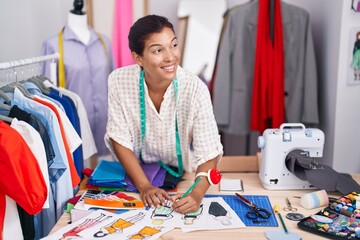 Young beautiful hispanic woman tailor smiling confident drawing clothing design at tailor shop