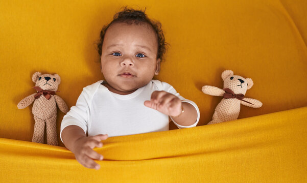 African american baby relaxing on bed with teddy bear at bedroom