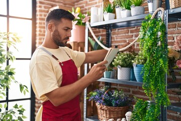 Young hispanic man florist reading notebook at florist