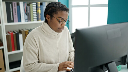 African american woman student using computer studying at library university