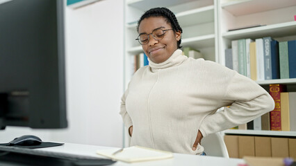 African american woman student using computer suffering for backache at library university