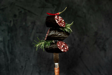 Black pudding or blood sausage with rosemary on a fork.