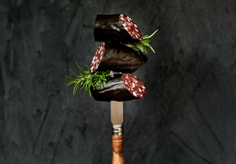 Black pudding or blood sausage with rosemary on a fork.